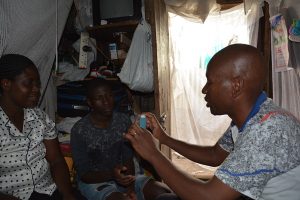 Alfred demonstrating usage of an inhaler to Rose and her son, Ochieng